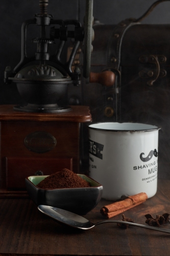Vintage coffee grinder, coffer and coffee cup over wood in a dark enviroment
